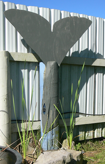 Wooden post and metal dolphin tail garden sculpture