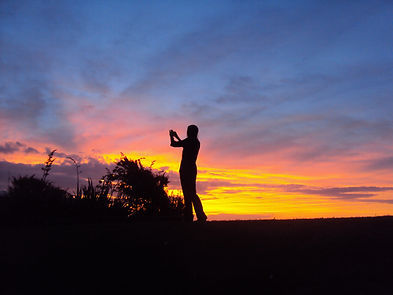 Silhouette of person taking photo at sunset