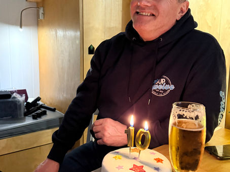 A man with a cake, candles and drink