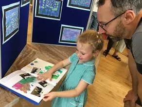 A young girl shows her Dad a piece of artwork in her art folder.