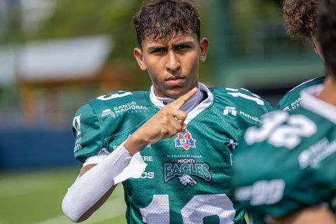 Young athlete in green football jersey, pointing upward.