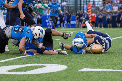 Football players tackling on the field.