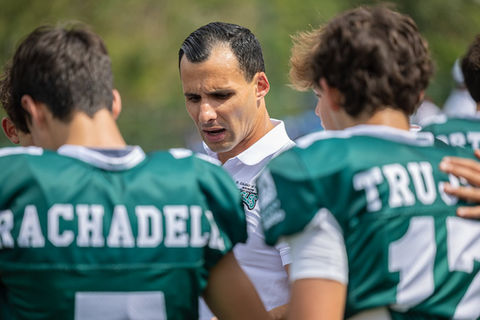 Coach instructing football players on the field.