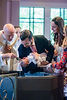 Dad cradles baby over baptismal fount as deacon pours water.