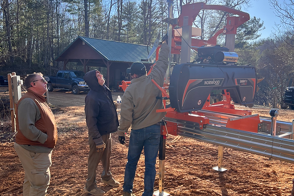 Three men examining a large sawmill