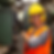 A woman worker with her personal protective equipment smiling next to a machine control box.
