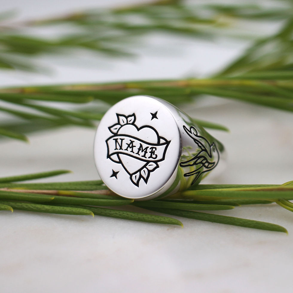Thumbnail: A round silver signet ring with a tattoo style heart engraving with a customisable banner with old school tattoo writing.