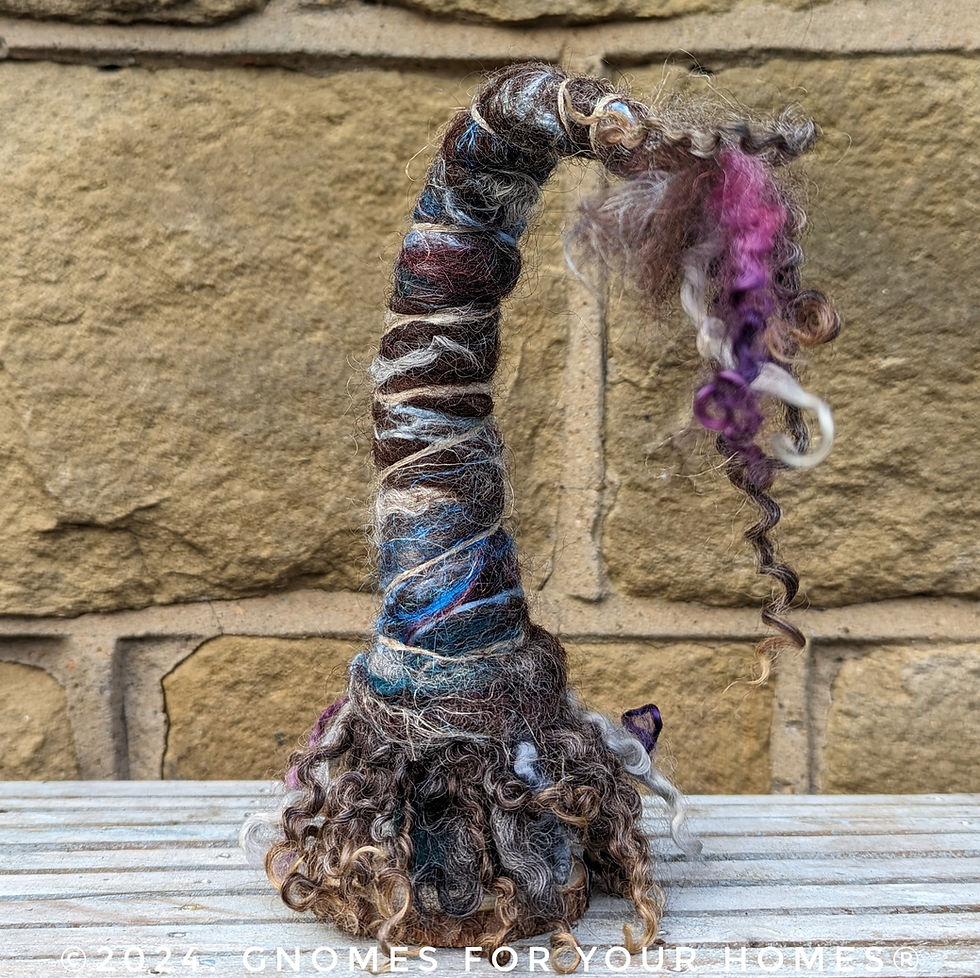 Thumbnail: hand felted gnome with pointed hat in brown, grey and blue colours.  He has long shaggy dark brown locks