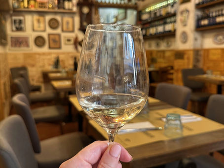 A glass of prosecco held up inside Trattoria Vecchio Griglia, Florence.