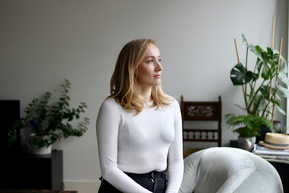 Blonde woman in white top looking out of window