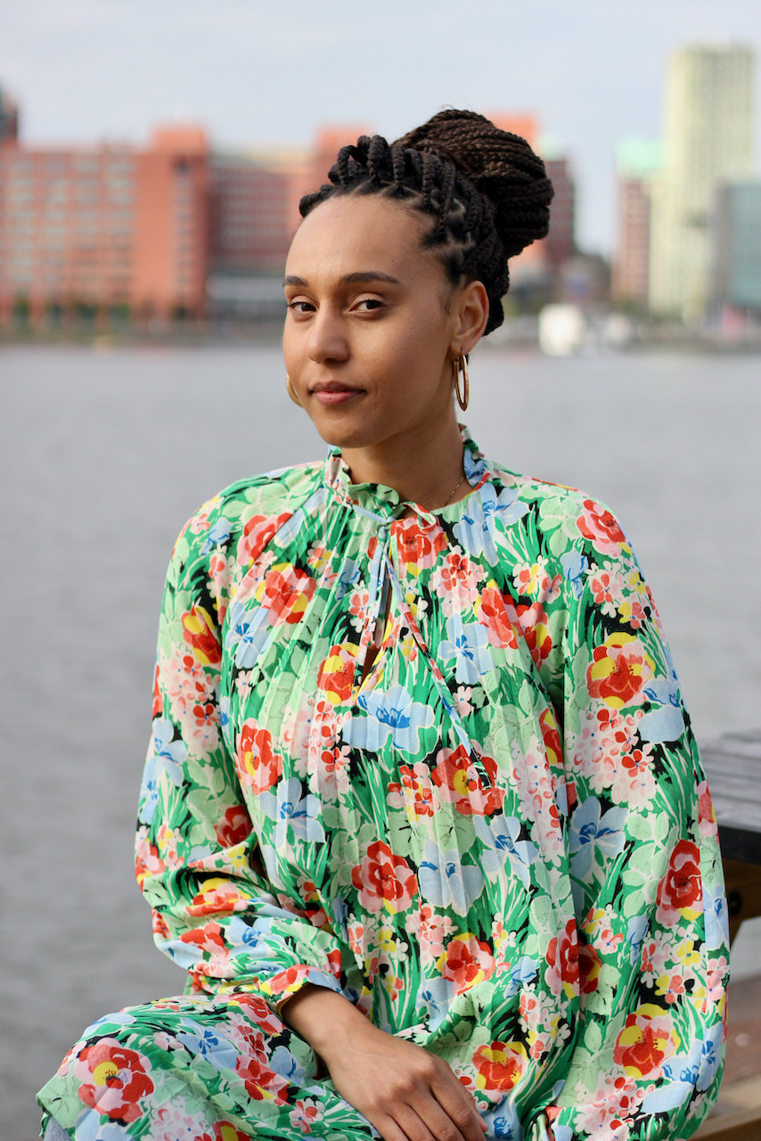 Woman in floral dress sits next to lake