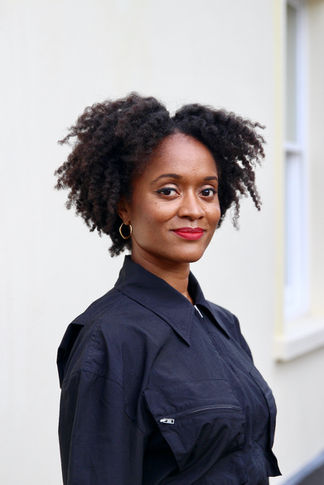 portrait photographer Brighton black woman with red lipstick and black shirt in front of white wall
