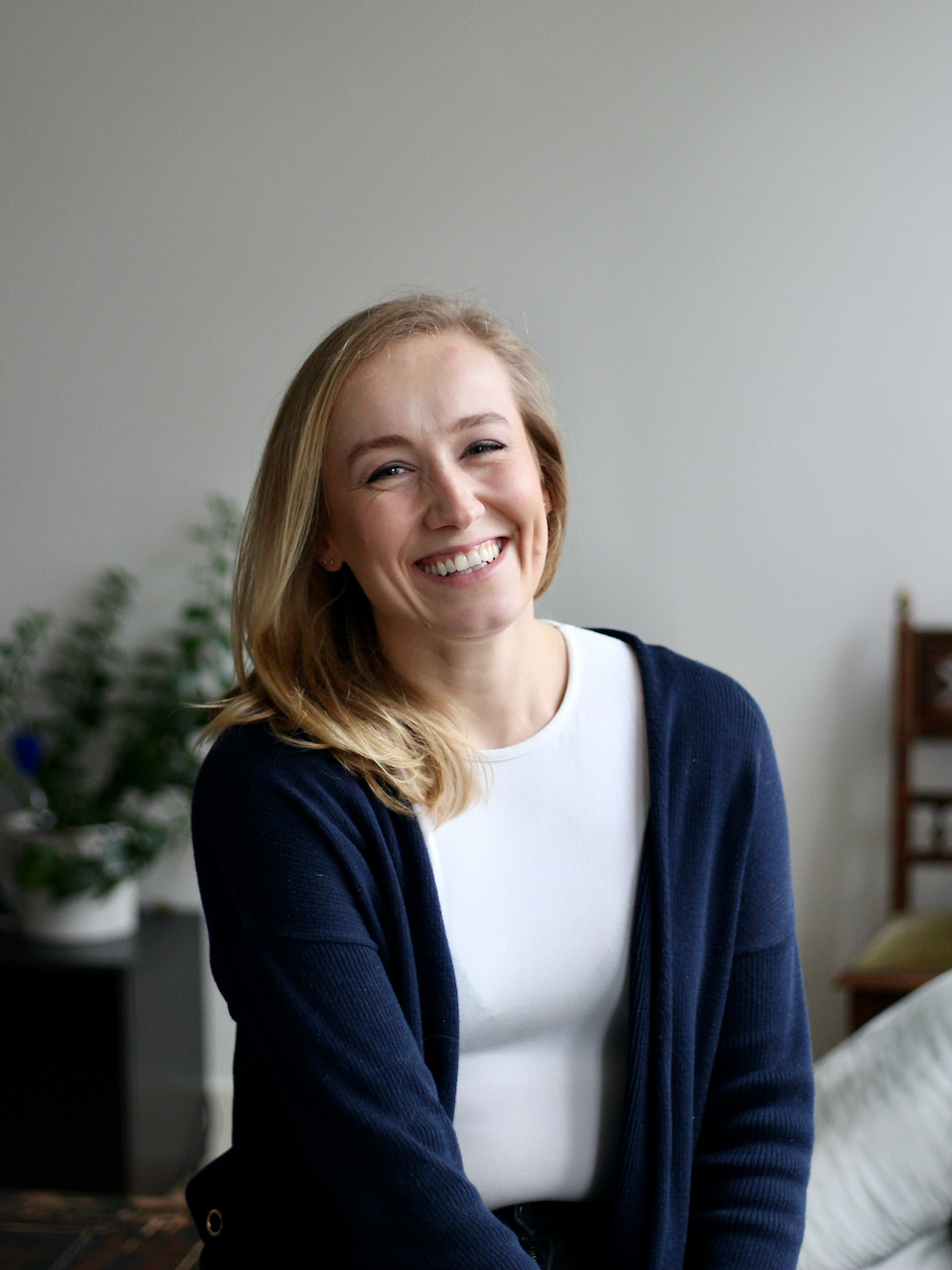 Blonde woman in white top and blue cardigan smiling