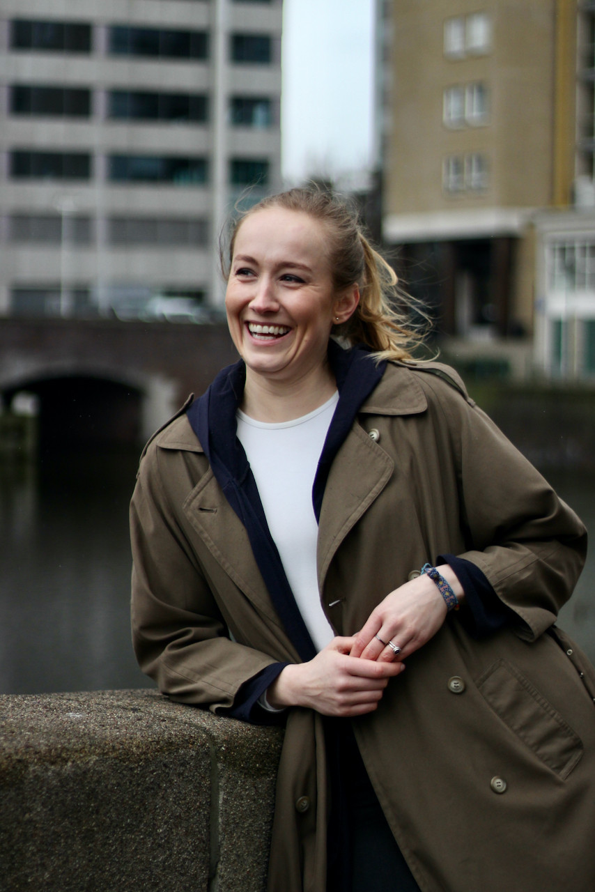 Blonde woman leaning on stone wall in front of bridge