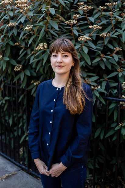 woman in navy shirt in front of flowering shrub headshots brighton
