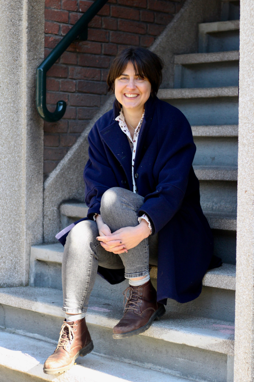Woman in navy coat sits on stone steps