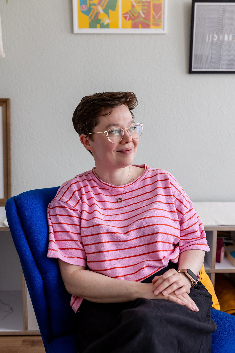Creative personal branding white woman glases short brown hair pink tshirt sitting in blue chair