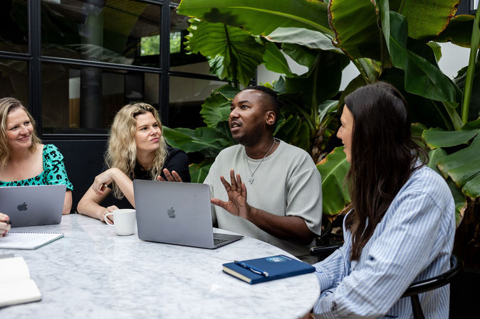 portrait photographer Brighton team meeting in front of laptop and large plant