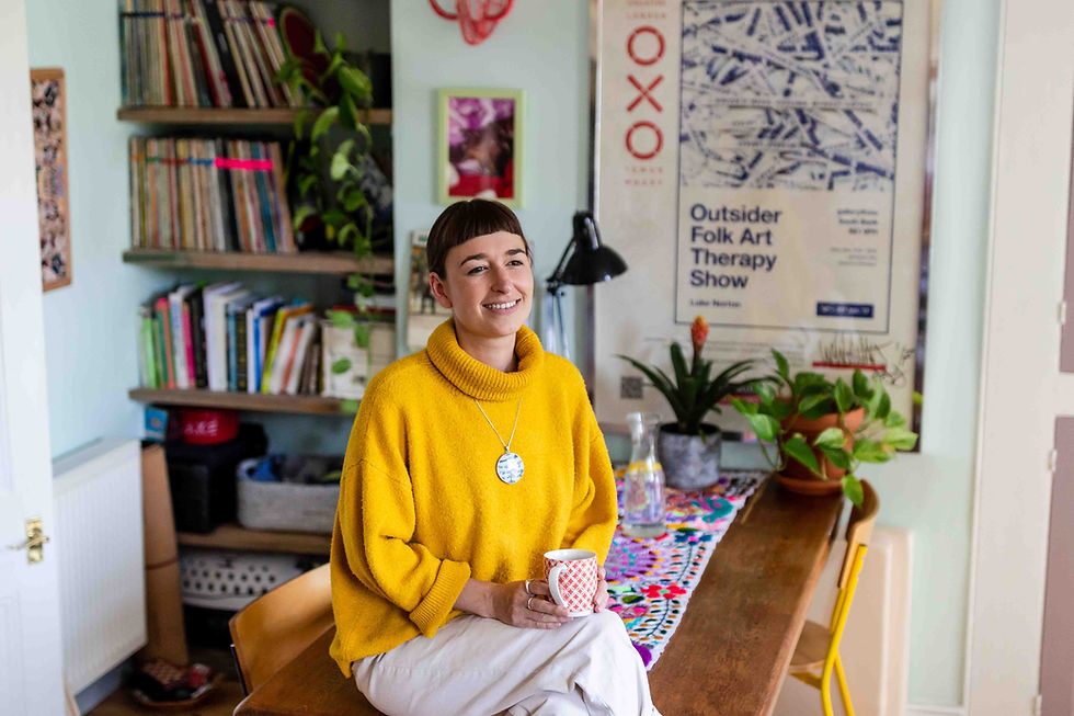 Woman in yellow jumper and white jeans sitting on table with mug of tea