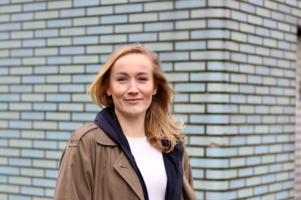 Blonde woman in front of pale blue tiled wall