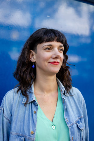 Brighton headshot photographer white woman with dark curly hair and red lipstick in front of blue door
