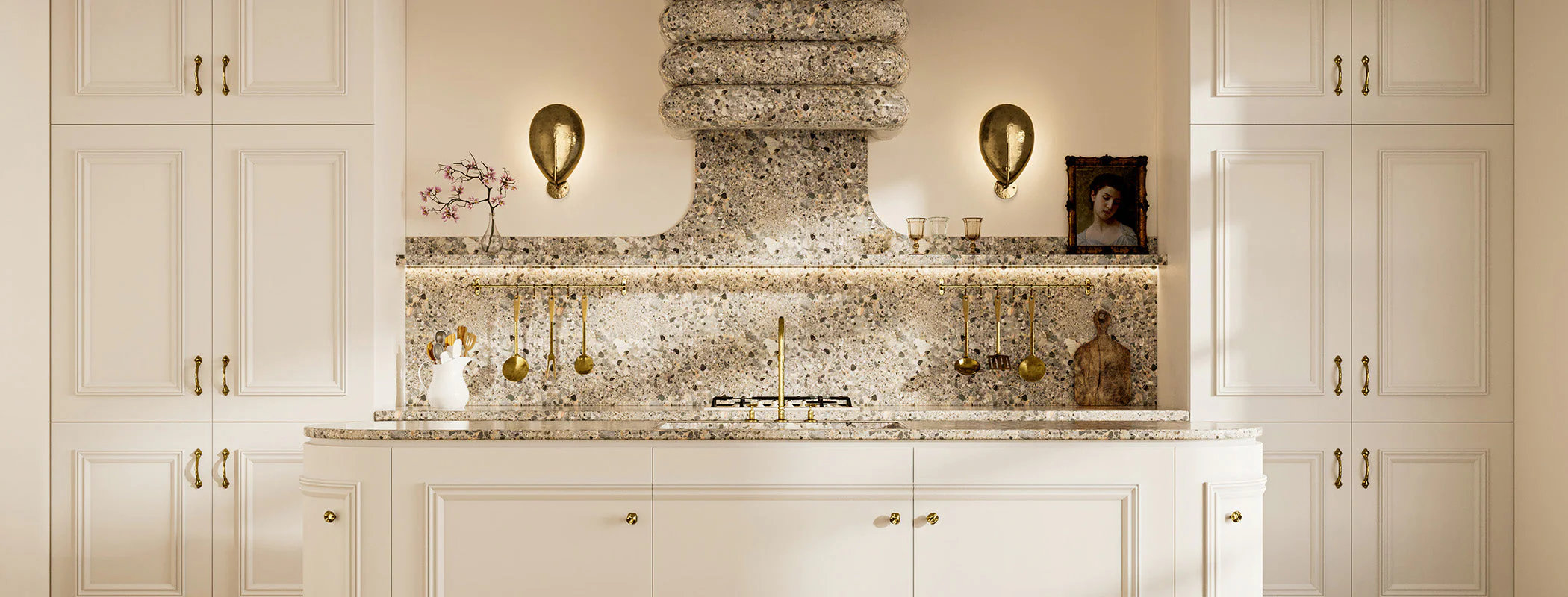 Classic kitchen renovation with white cabinetry, terrazzo backsplash, decorative range hood, and gold hardware