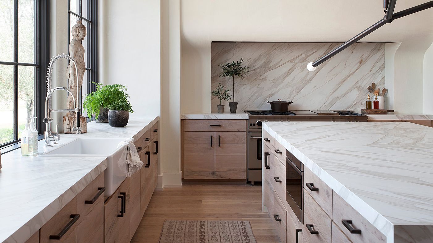 Modern kitchen renovation with wood cabinets, marble countertops, large island, and farmhouse sink near window