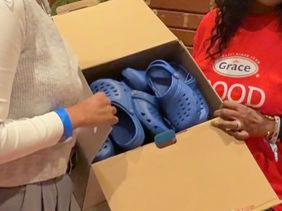 Woman hands over box of shoes to a woman