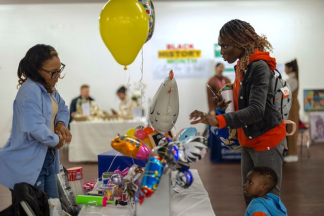 Balloon craft business owner talks with a customer about her products from behind her stall