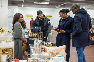 Luxury hamper business owner talks with customers about her products from behind her stall