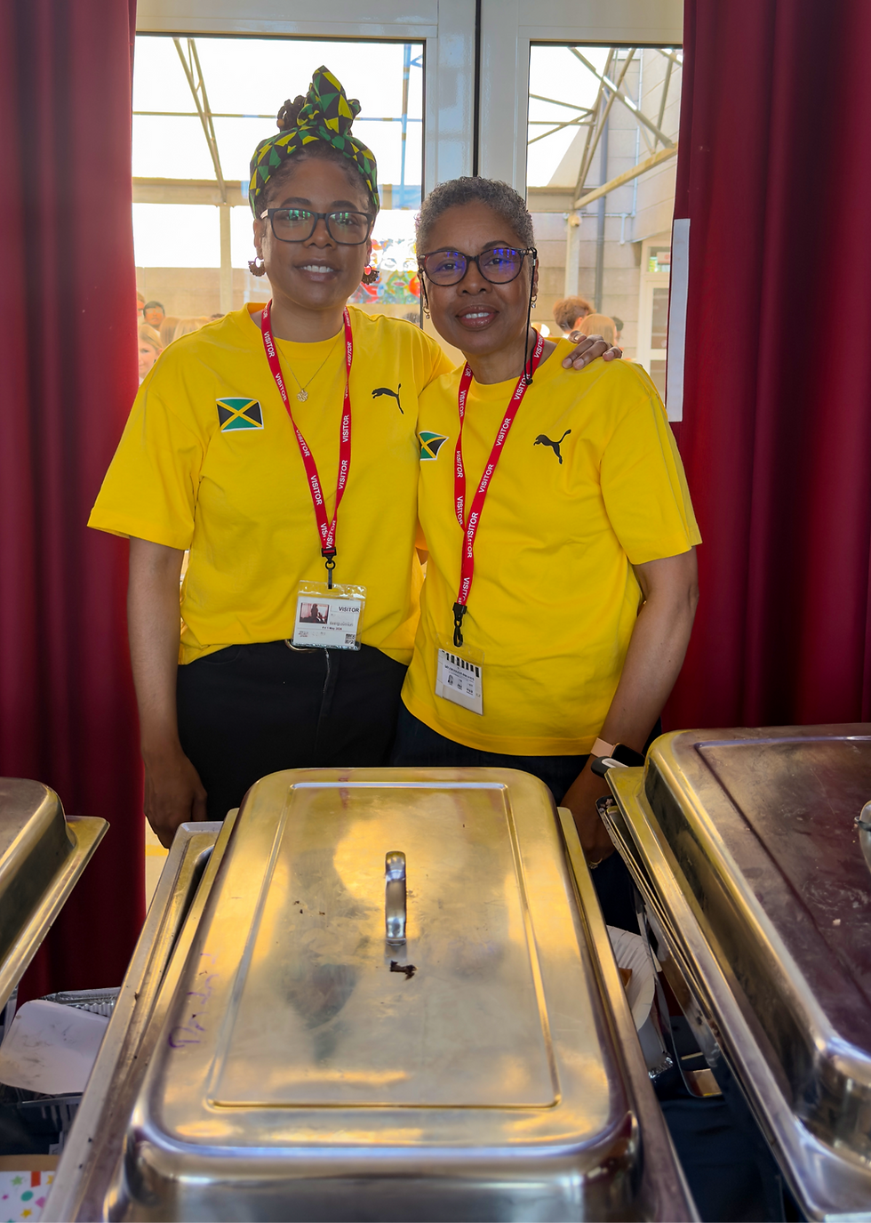 Two women in the yellow t-shirts with the Jamaican flag on it , pose for a photo