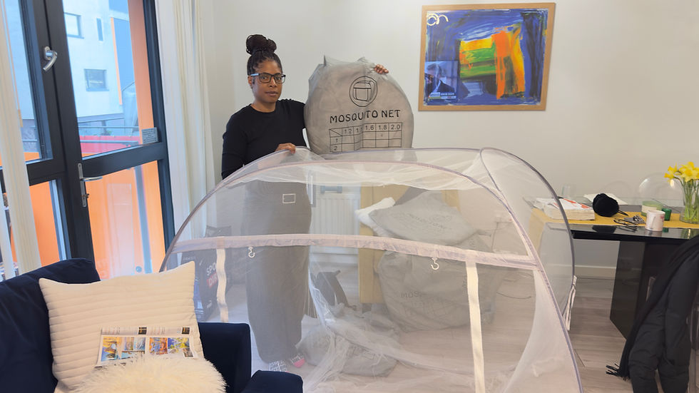 Woman standing in front of a pop up family size mosquito net and holing one folded  in it's  carry bag 