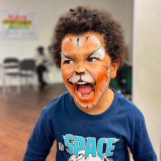 Little boy with his face painted like a tiger roars