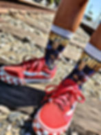 A picture of a kid in red shoes with fortnite socks on by the train track