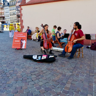 Jairo Ortiz und Laila Kirchner spielen linkshändig Cello vor der Alten Nikolaikirche in Frankfurt
