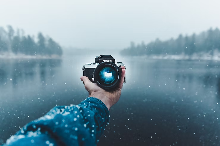 Hand holding camera, snowy landscape in viewfinder