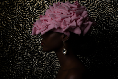 Woman in profile wearing a pink floral hat and Avant Garde Fashion with earrings
