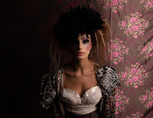 Woman wearing avant garde fashion with flower print backdrop, portrait of Eti Brener.