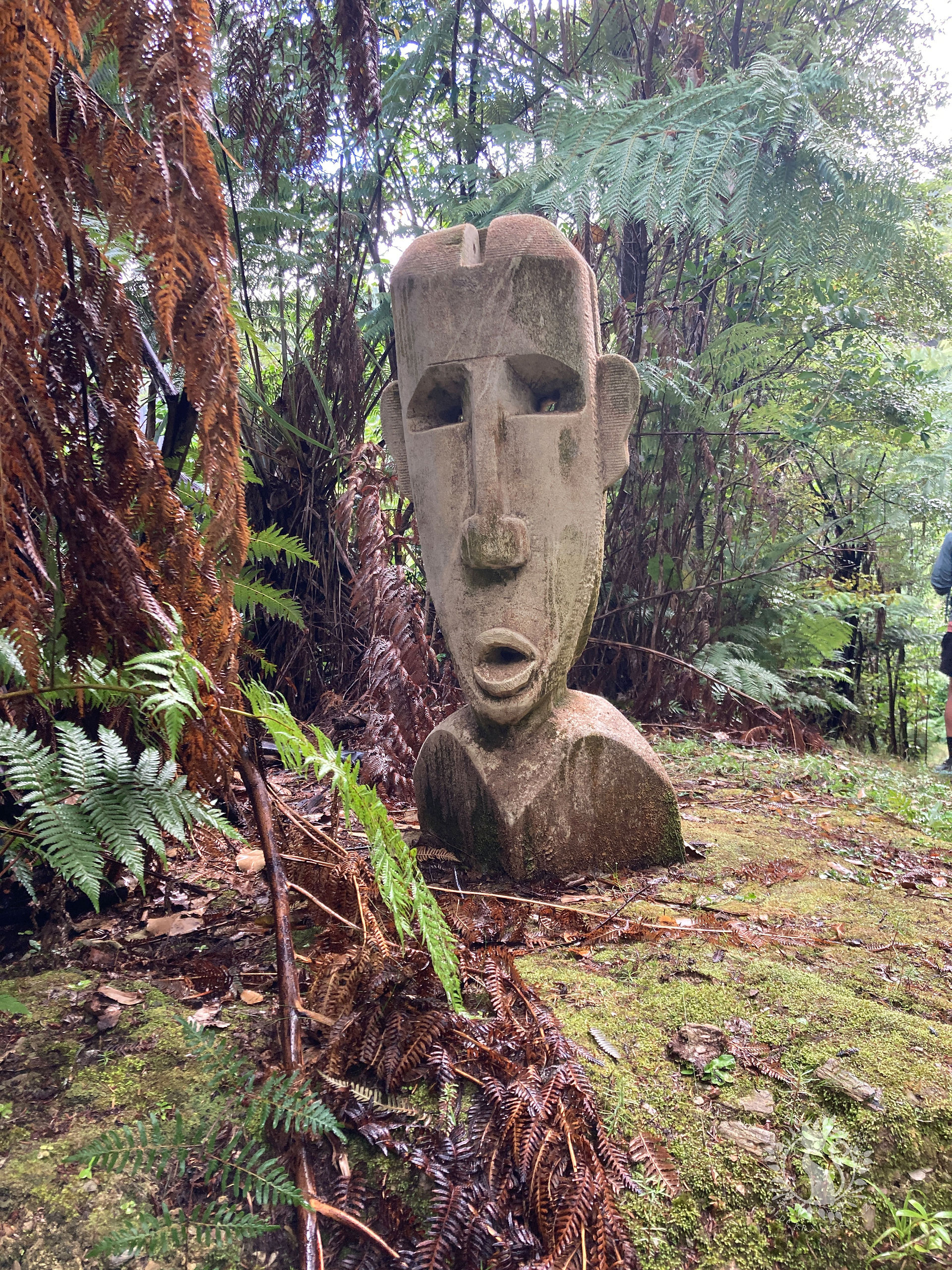 Steinstatue einer Maori Gottheit im Regenwald Neuseelands
