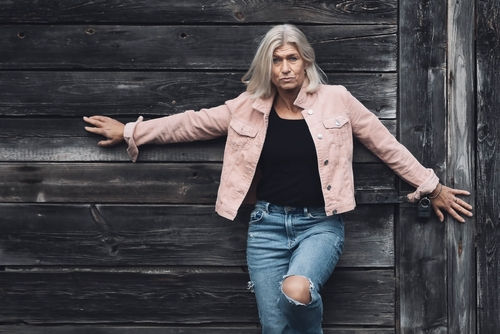 Attractive older white woman standing in a defiance stance against a barn