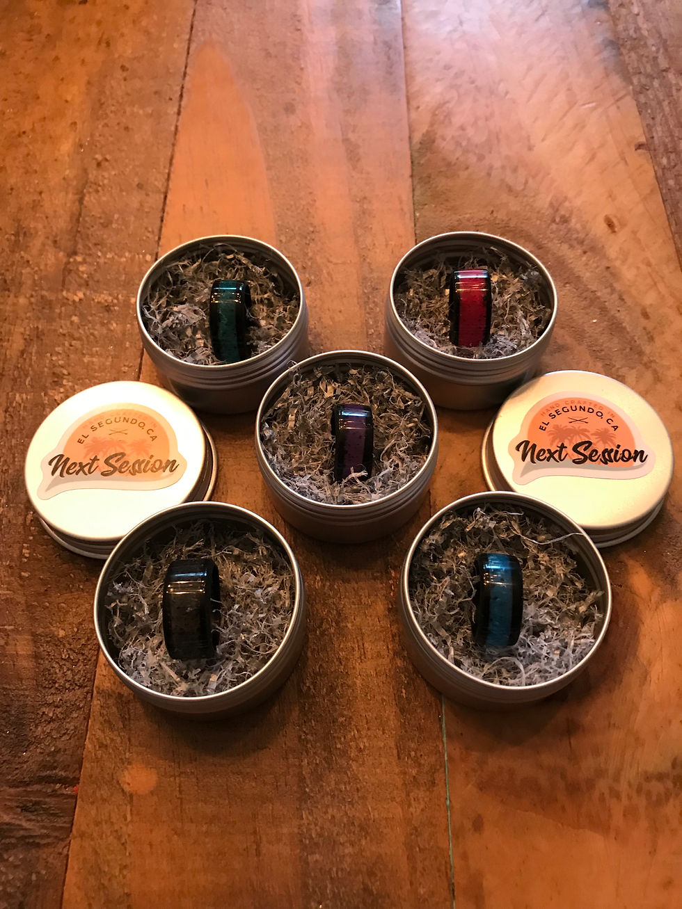 Next Session rings in various colors displayed in their tins
