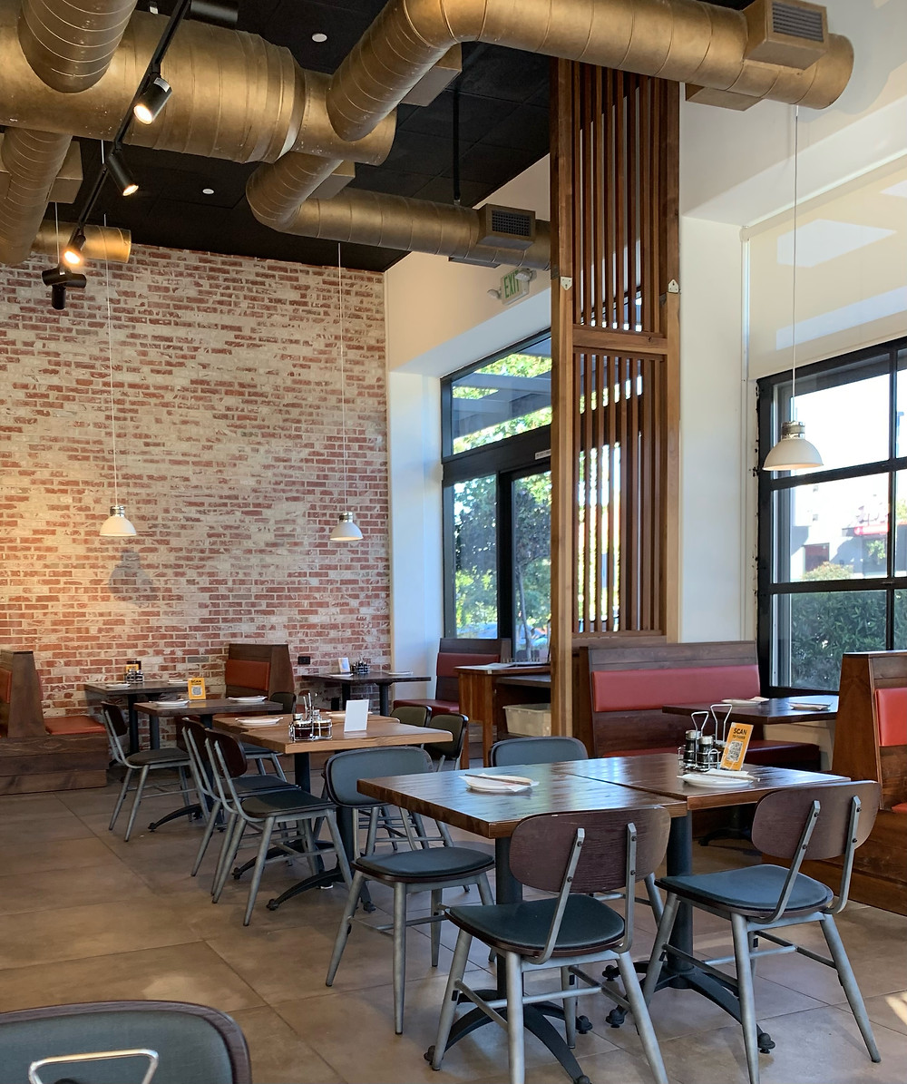Exposed brick wall, high industrial-style ceiling, well-lit dining space in Northern Cafe in El Segundo