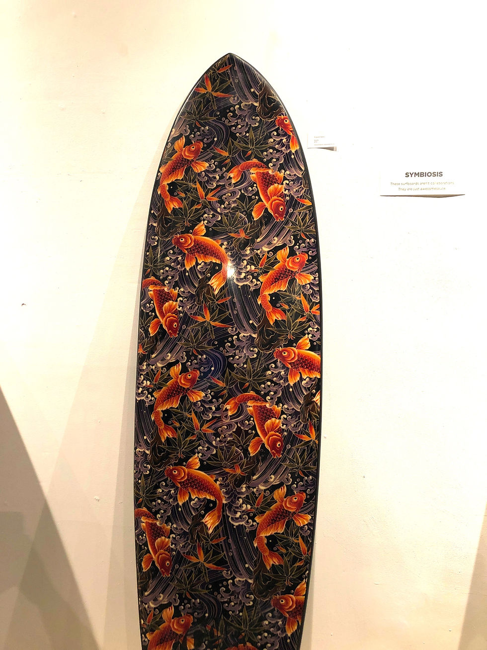 A Daley Shapes surfboard on display at Resin art gallery in Hermosa Beach. Board is decorated with Koi fish and underwater plants.