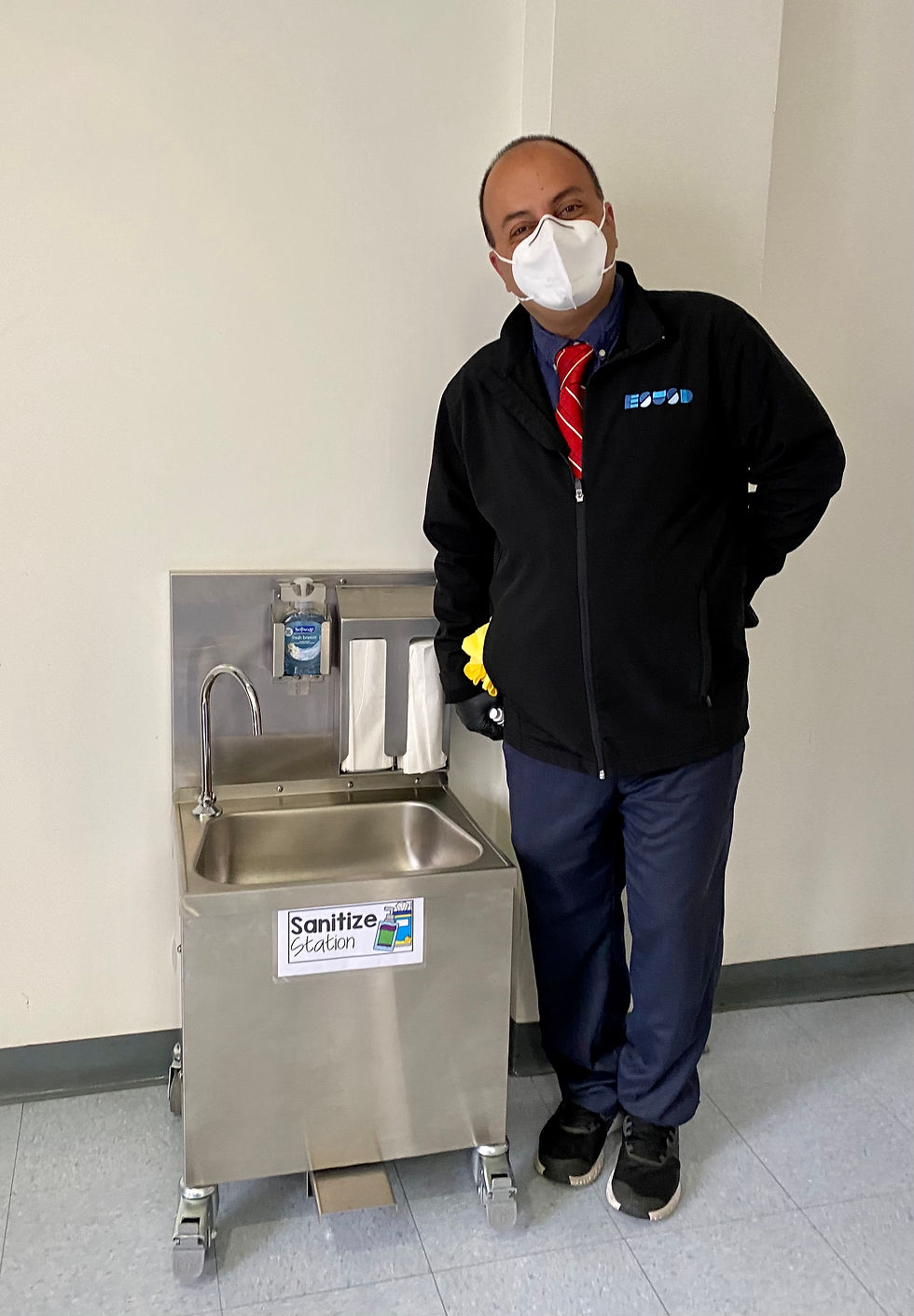 Ali Rabiei poses next to a scaled-down hand-washing station for kindergarten students.