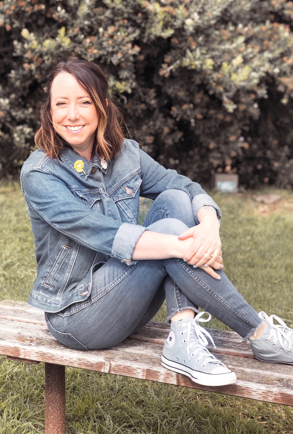 Artist and maker Aja De La Rosa poses on a bench outdoors