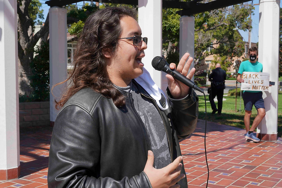 Elias Garcia speaks at microphone in Library Park in El Segundo California