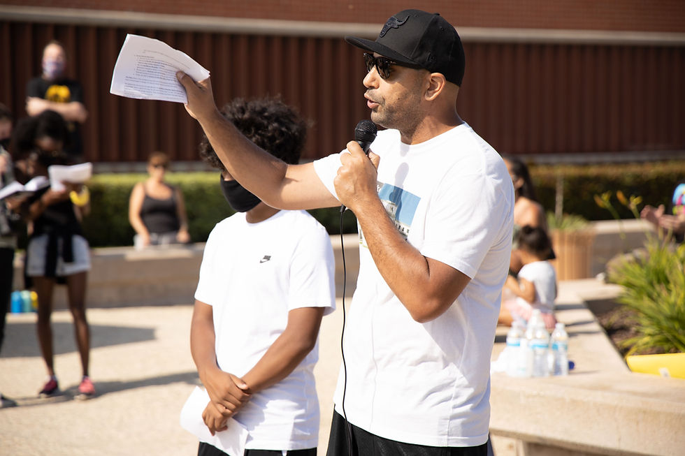 Keith Puckett speaks to a crowd at a microphone in El Segundo's Civic Center