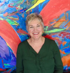 Abstract painter Phyllis Ferrara stands in front of one of her bright, primary-color abstracts