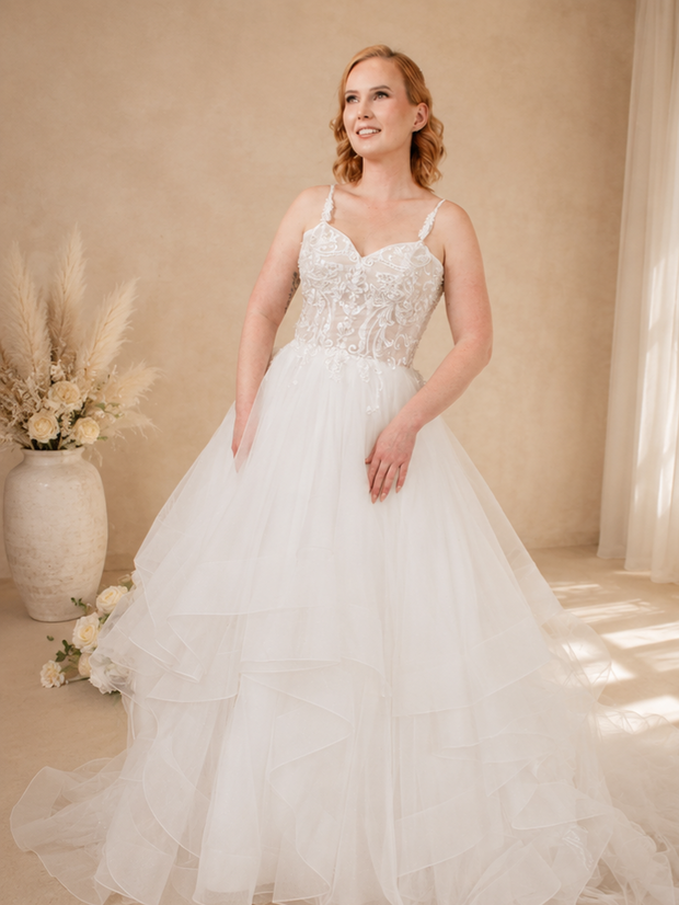 Ella wedding dress with sweetheart neckline, sheer bodice, delicate lace straps, and dramatic waterfall skirt for a romantic elegant bridal look.