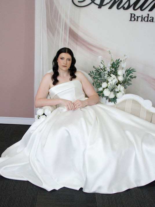 Mikado A-line wedding gown with box pleat skirt, strapless bodice, and bold decorative fold for a classic bridal look.